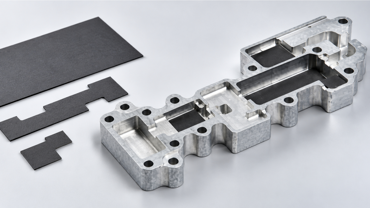 Custom-cut microwave absorber material beside an aluminum RF equipment cavity with fitted absorber inserts.